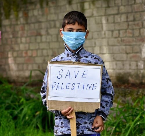 Photo by Hurrah Suhail at pexels.com/photo/boy-in-facemask-holding-placard-12018419/